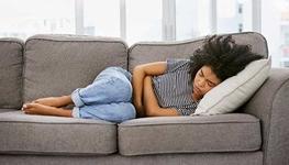 Woman laying on the couch with stomach cramps